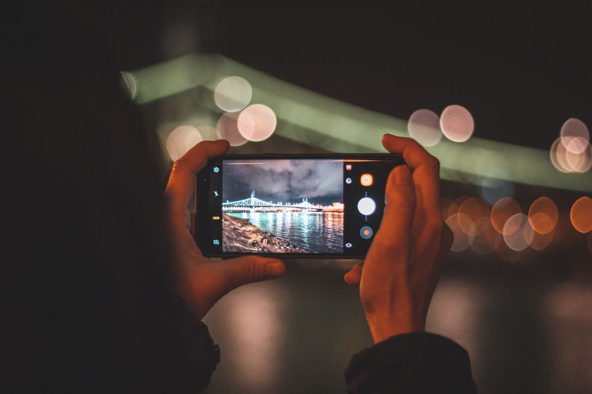 Elde tutulan akıllı telefon ekranı parlayan ışıklar arka planında