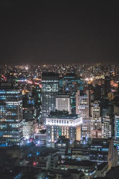 A stunning night cityscape showcasing illuminated skyscrapers and vibrant city lights under a dark sky.