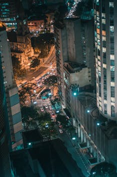 夜晚的街道灯火通明，现代摩天大楼构成了一幅戏剧性的城市鸟瞰图