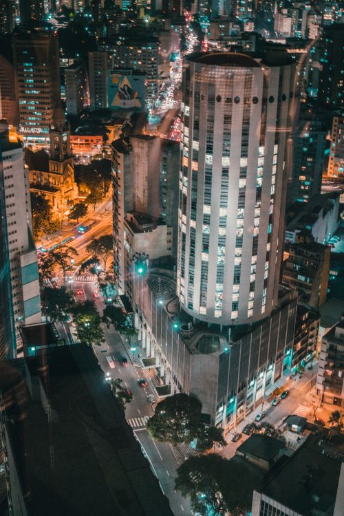 Free A stunning aerial view of a busy urban cityscape at night with illuminated skyscrapers and bustling streets. Stock Photo
