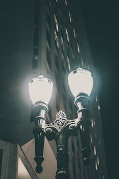 A classic street lamp casts a glow on a city street at night, enhancing the urban ambiance.