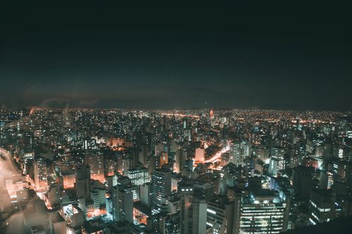 Free A breathtaking aerial view of city skyscrapers illuminated at night, showcasing urban life and glowing city lights. Stock Photo