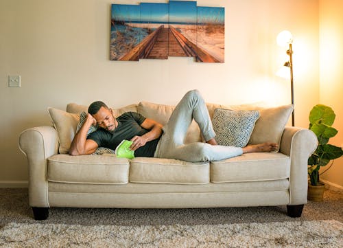 Man lying on Couch while Reading a Book