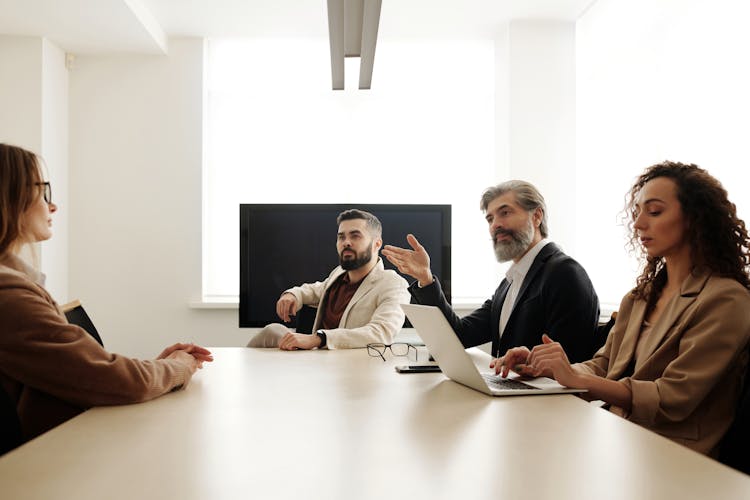 A Group Of People Sitting At The Table At A Business Meeting 