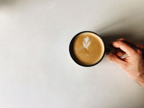 Free Top view of a latte with art held over a white surface. Minimalistic and calming. Stock Photo