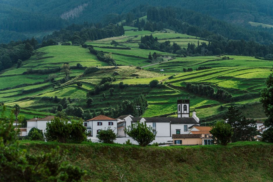 Scenic rural landscape with lush green hills and houses in the Azores, Portugal.