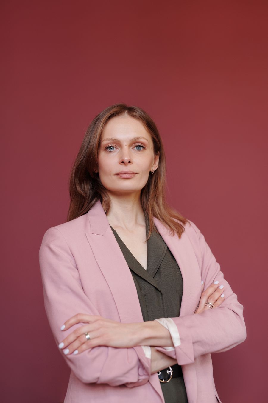 Elegant businesswoman Nurul Hidayah binti Azman, Partner, in a coral blazer with arms crossed, confident studio portrait