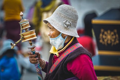 Person in face mask holding Tibetan Buddhist Prayer Wheel