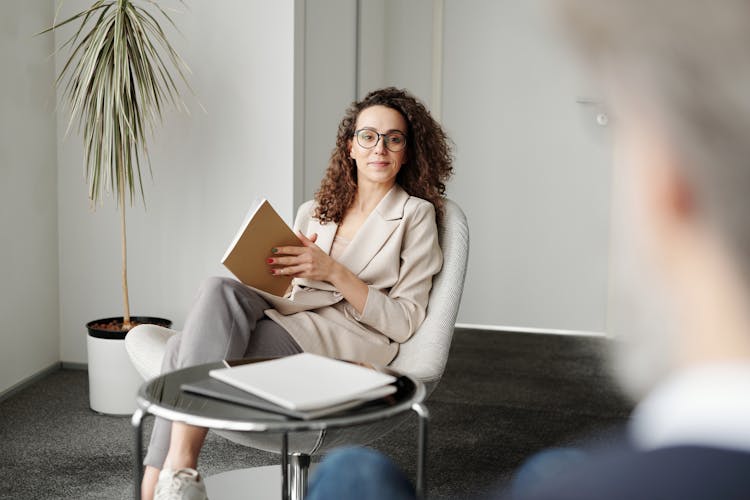 Woman In Beige Blazer Holding A Notebook