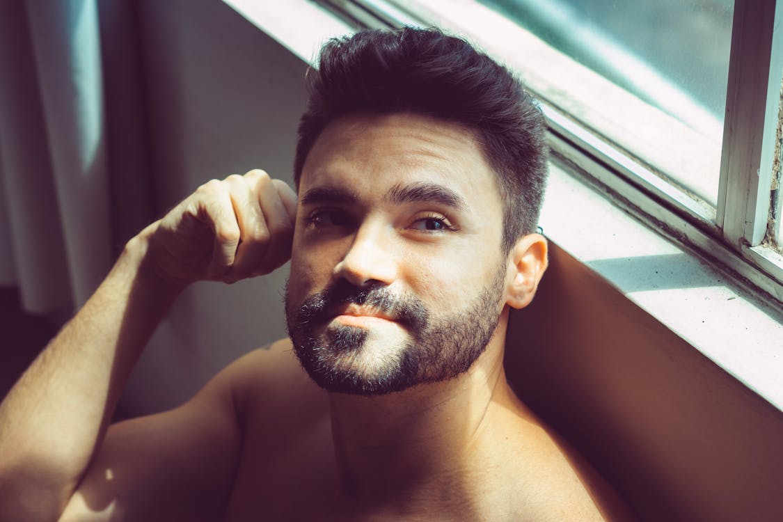 Free Shirtless man relaxing next to window Stock Photo