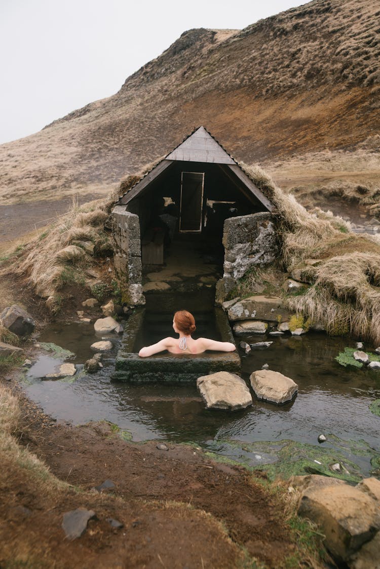 Unrecognizable Woman Resting In Stone Bath Tube Near Mountains