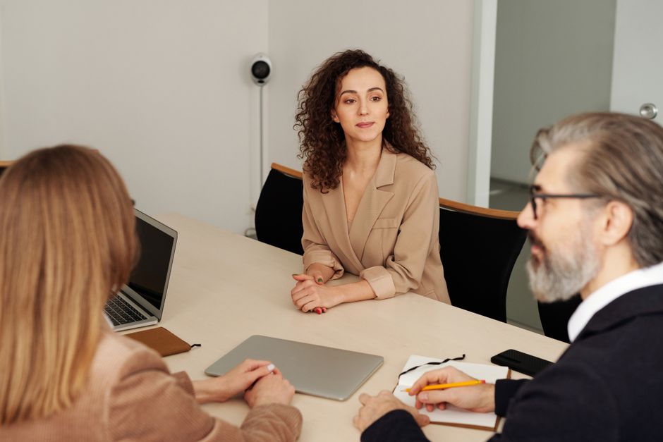 Tres colegas discutiendo ideas alrededor de una mesa en un entorno de oficina.