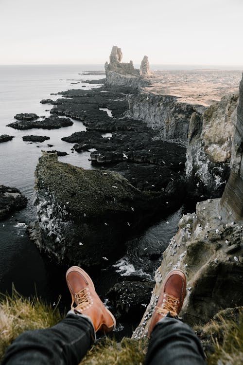 Unrecognizable man sitting on rocky cliff at seaside