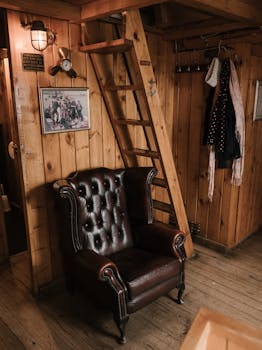 Explore the charm of a vintage interior featuring a leather armchair, wooden ladder, and classic decor.