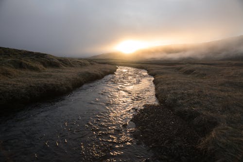 Calm river flowing on plain at sunset