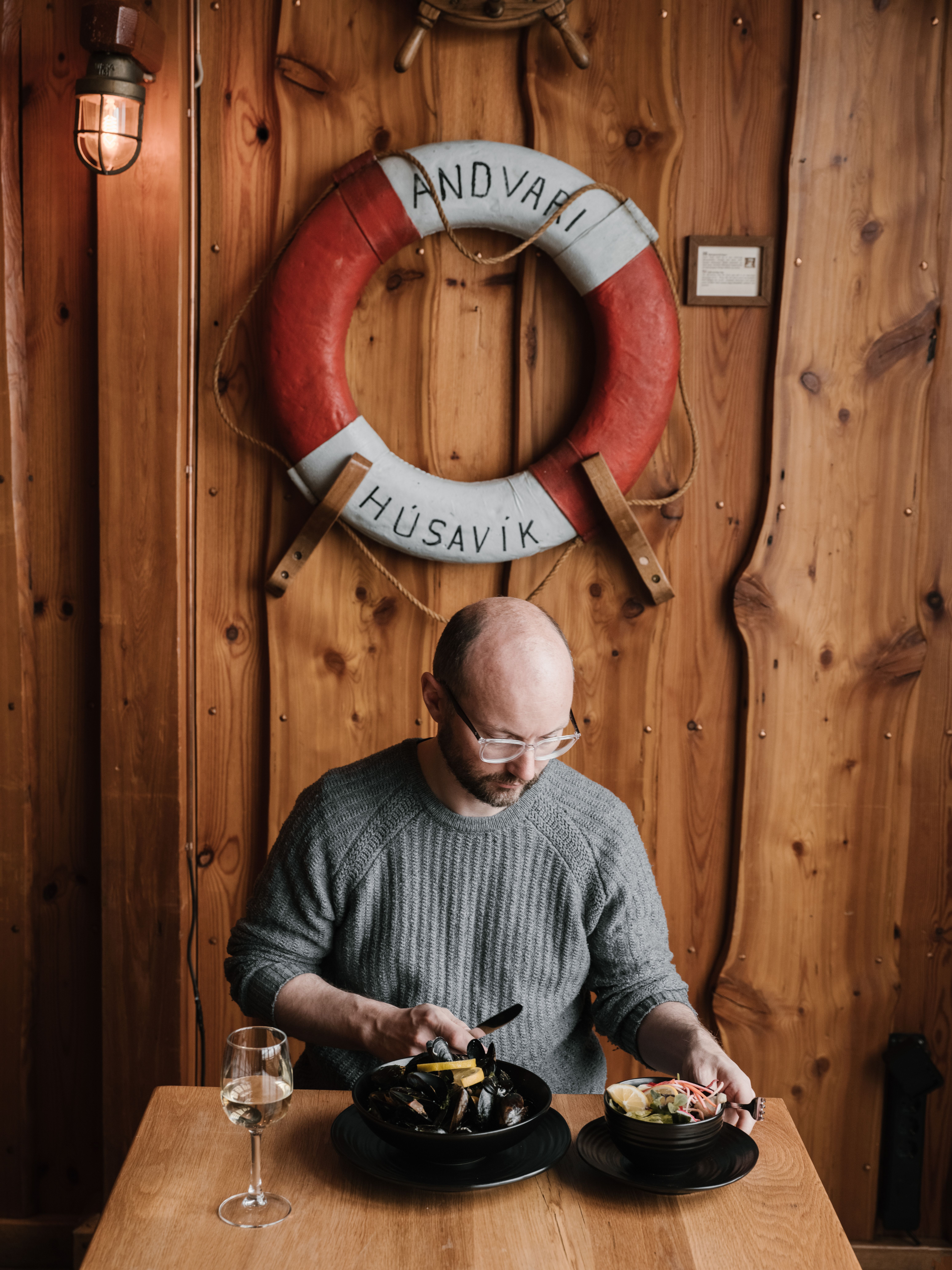From above of bearded man in eyeglasses and casual sweater sitting at table and enjoying delicious dinner in contemporary restaurant