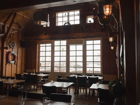 Interior of modern cafe decorated by wooden panels with large windows in Dutch style and items from old sea ship