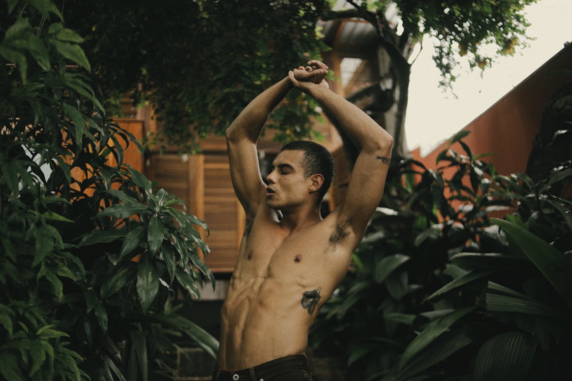 Topless Man Standing Near Green Plants and Trees