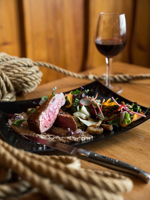 Delicious meat steak served with vegetable salad and glass of wine