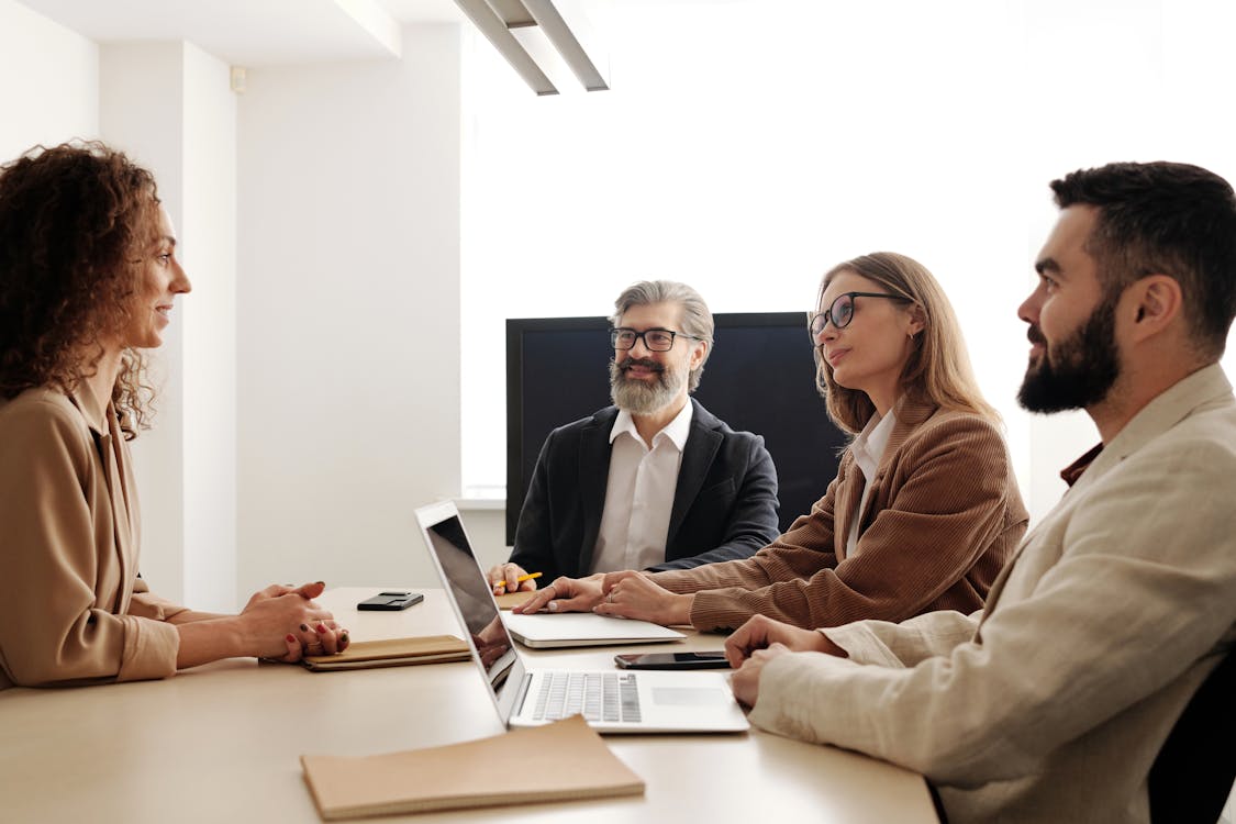 Free Man and Woman Sitting on Chair in Front of Macbook Pro Stock Photo