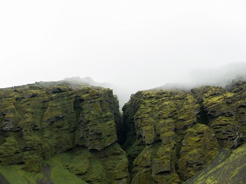 Free Majestic rocky slopes of mountains with moss on surface covered by fog in overcast weather Stock Photo