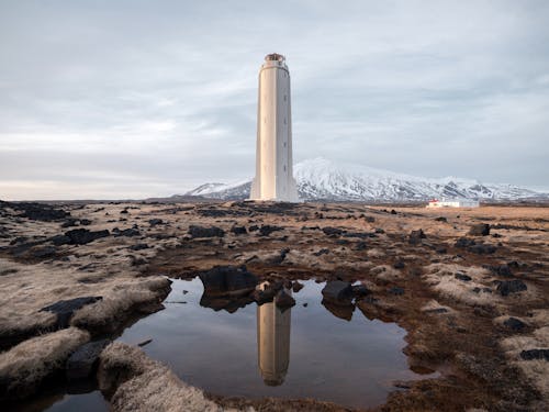 Lighthouse on remote seashore against snowy mountain