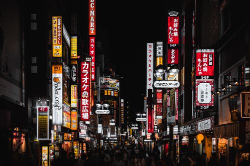 Free A bustling Tokyo street at night with neon signs illuminating the vibrant city atmosphere. Stock Photo