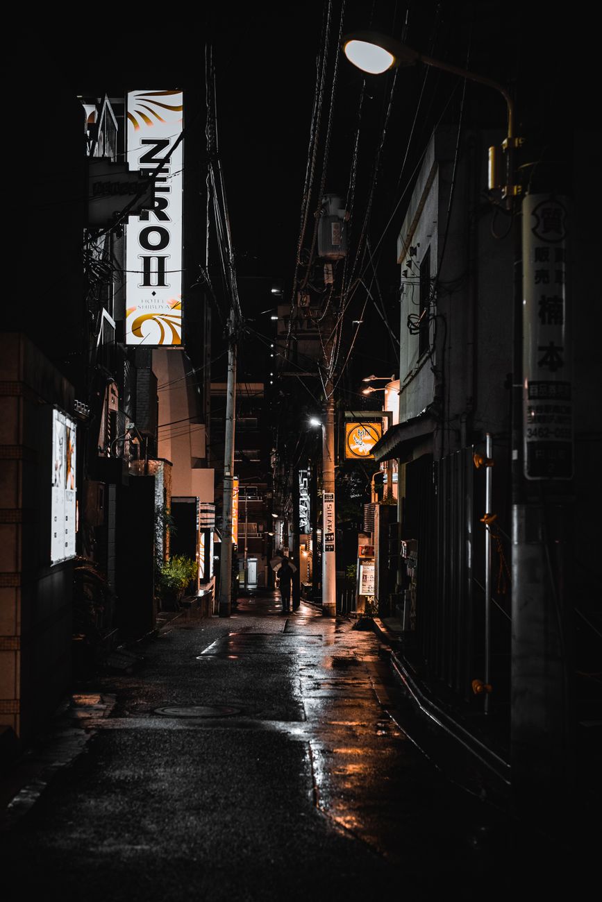 Explore the moody, illuminated streets of Tokyo at night, capturing the city's unique urban architecture.
