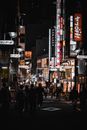 日本东京繁华的街道上，明亮的标志和行走的人们共同构成了一幅充满活力的夜景