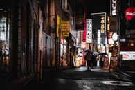 夜晚，人们在东京霓虹闪烁的街道上打着伞行走，捕捉这座城市充满活力的生活