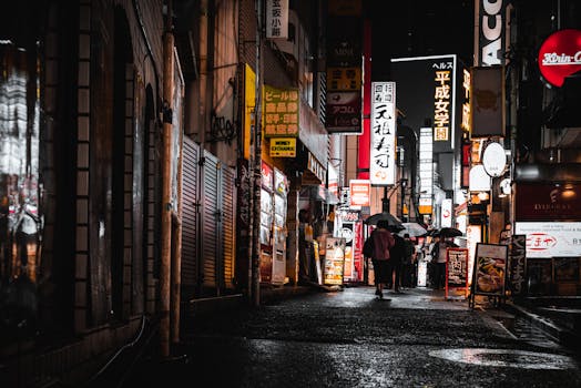 People walking under umbrellas in Tokyo's neon-lit streets at night, capturing the city's vibrant urban life.