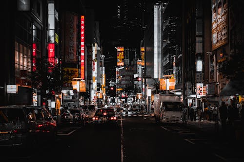 A Cars on the Road Between City Buildings at Night