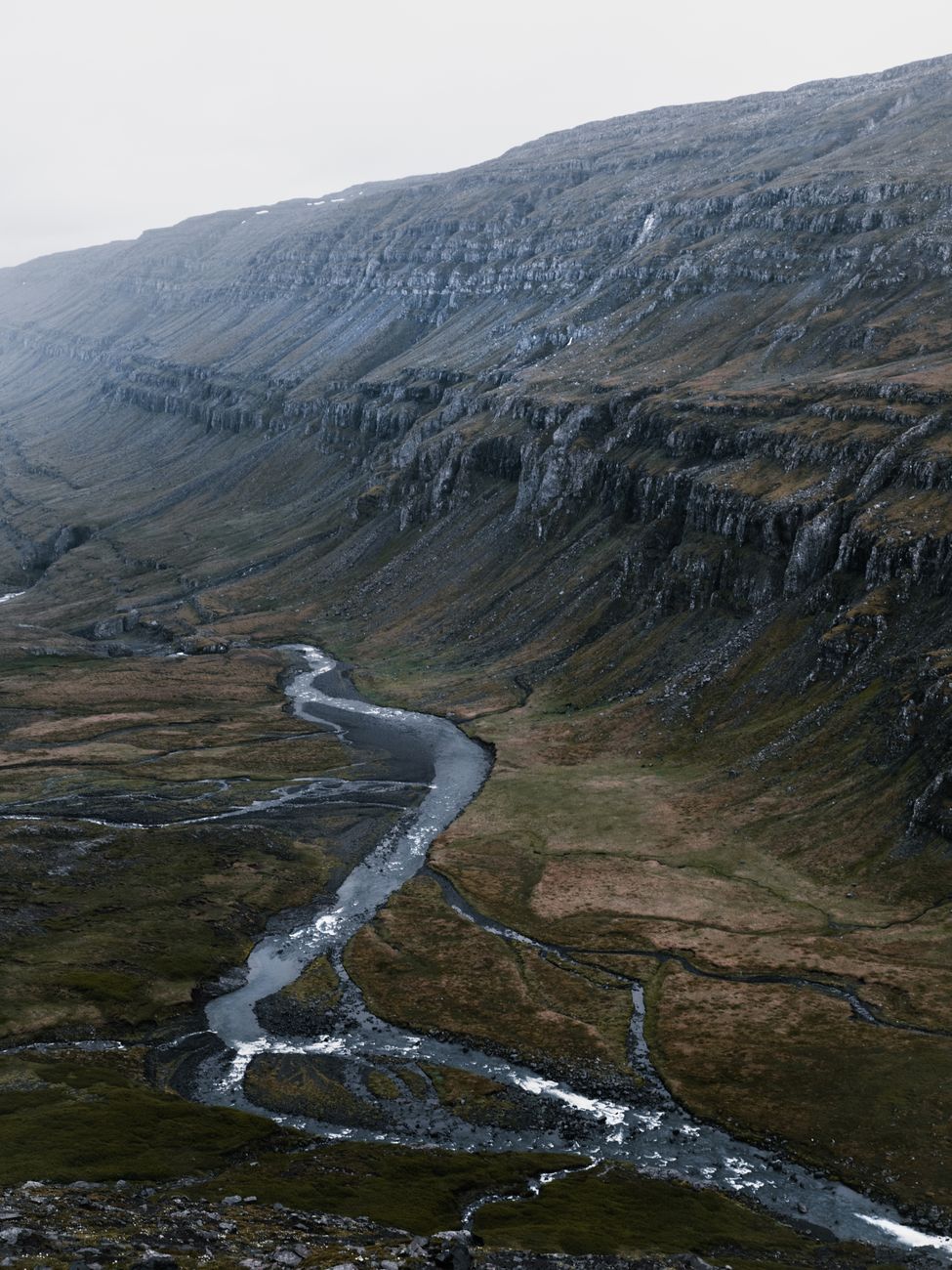 Picturesque view of narrow curvy rapid stream flowing through mountainous mossy terrain on cloudy morning