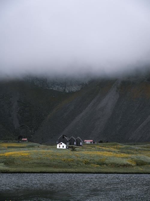 Remote houses on mountain valley under cloudy sky