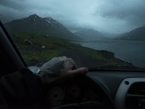 Unrecognizable driver in car near mountains during rain