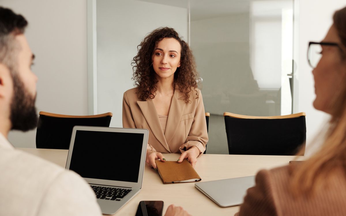 A woman in a business suit participates in a job interview, showcasing professionalism and modern office environment.