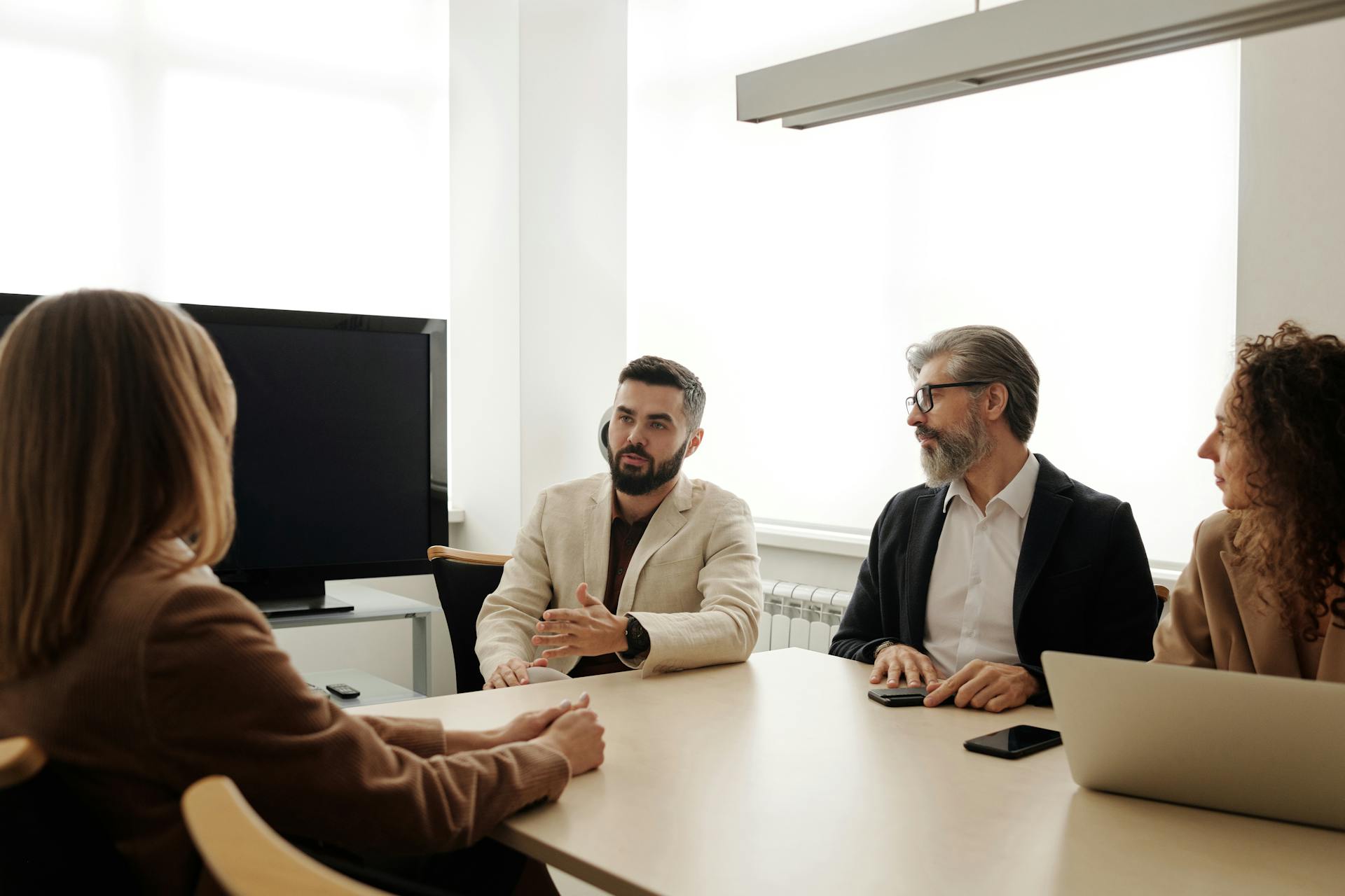 A diverse group of business professionals engaged in a meeting in an office setting.