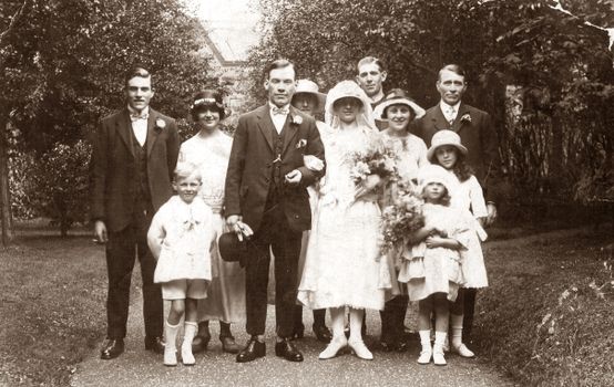 Charming vintage wedding group portrait featuring family members in a garden setting, classic attire.