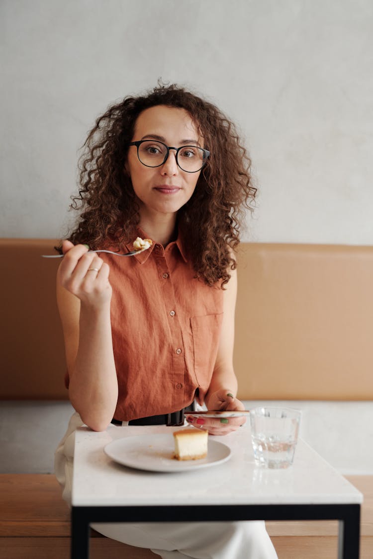 A Woman Eating Dessert While Using A Phone