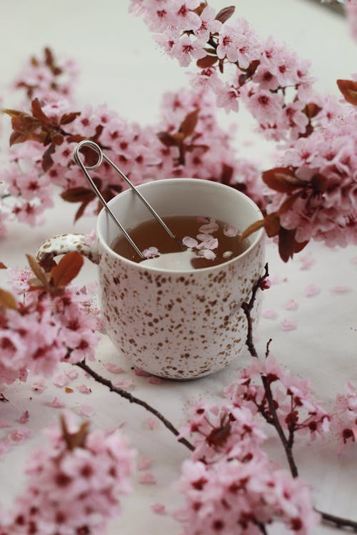 Spoon tea infuser in cup cup among flowers