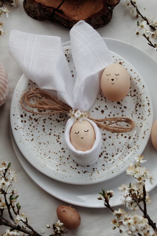 Free Creative Easter egg decoration with bunny ear napkins on speckled plates, surrounded by flowers. Stock Photo