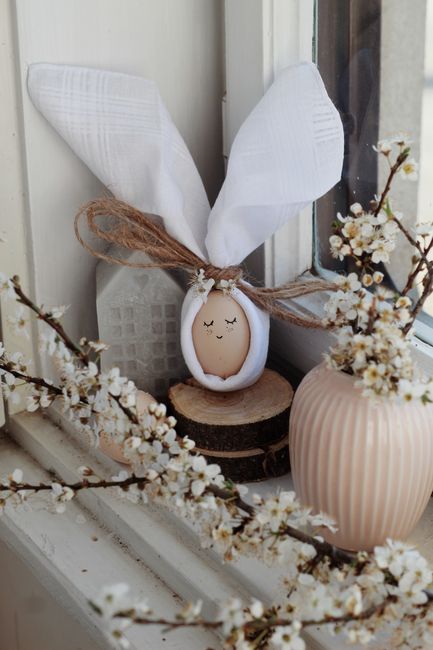 Creative bunny egg with smiling face arranged on windowsill with fresh flowers for Easter celebration