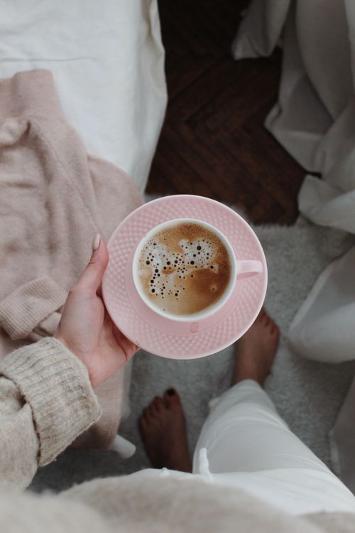 Free From above of anonymous crop female standing with mug of hot coffee with foam during breakfast in morning Stock Photo