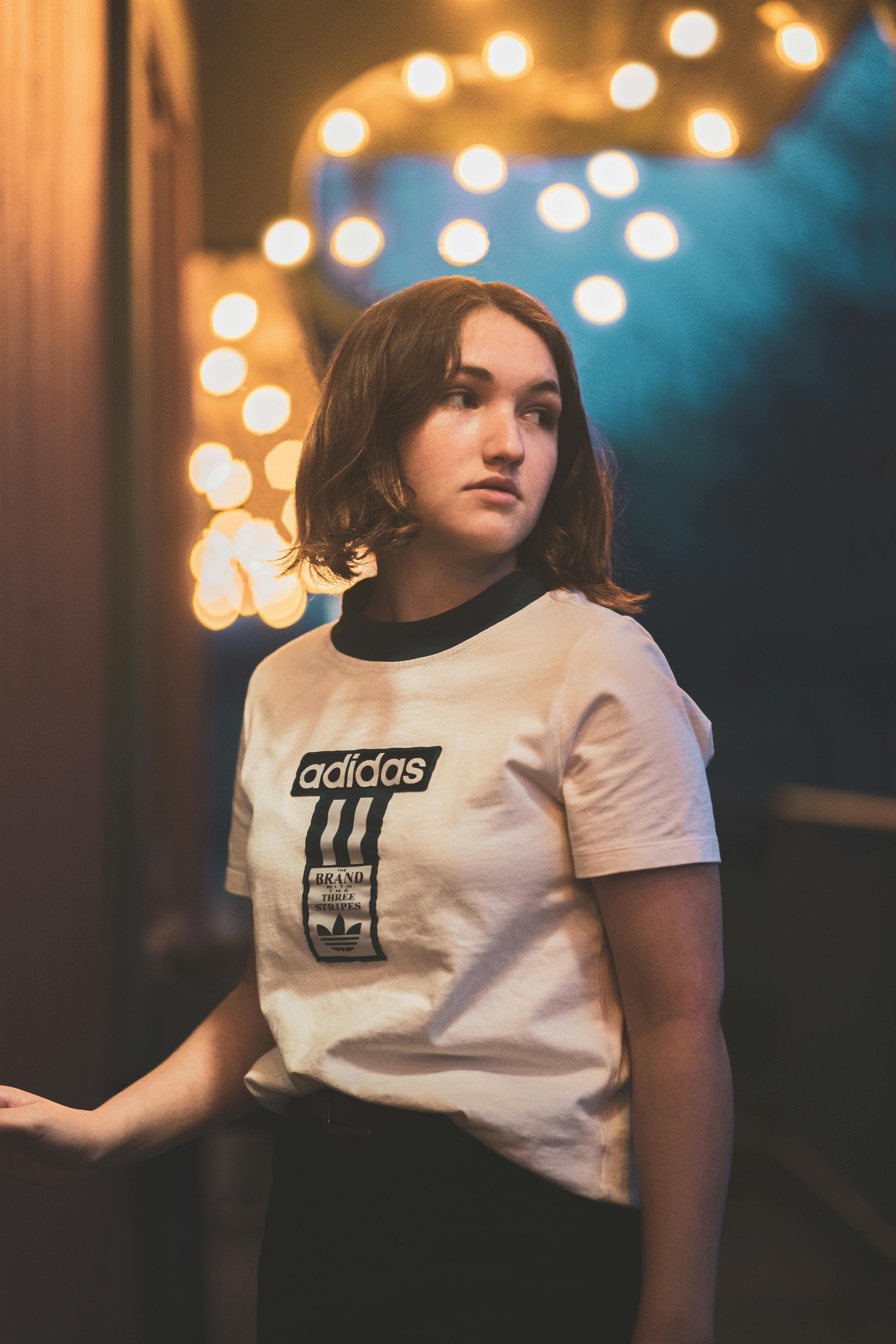 woman in white shirt standing near the wall