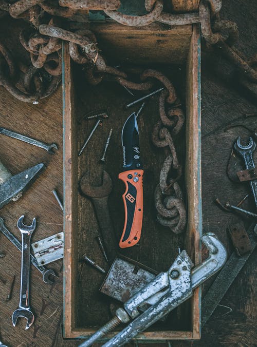 Top view of various carpentry tools arranged in shabby box and on wooden table