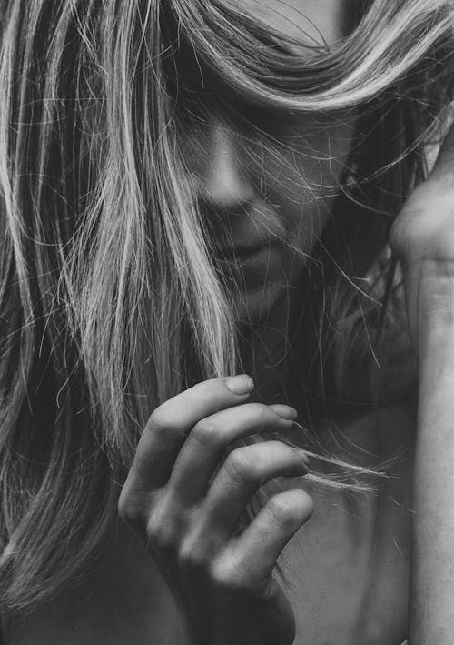 Grayscale Photography of a Woman Holding Her Hair