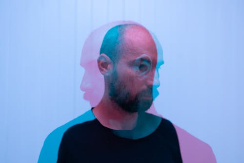 Free Through glass double exposure view of dreamy middle aged bearded male looking away on white background Stock Photo