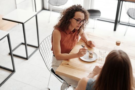 两个女人坐在咖啡桌旁，一边享用咖啡和甜点，一边交谈