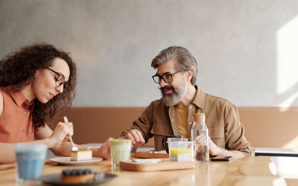 A man and woman enjoying desserts and drinks in a café setting, captured naturally.