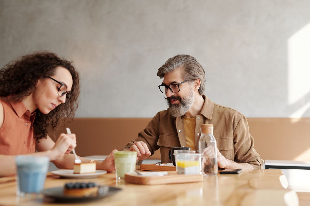 Two people in conversation at a coffee shop table.